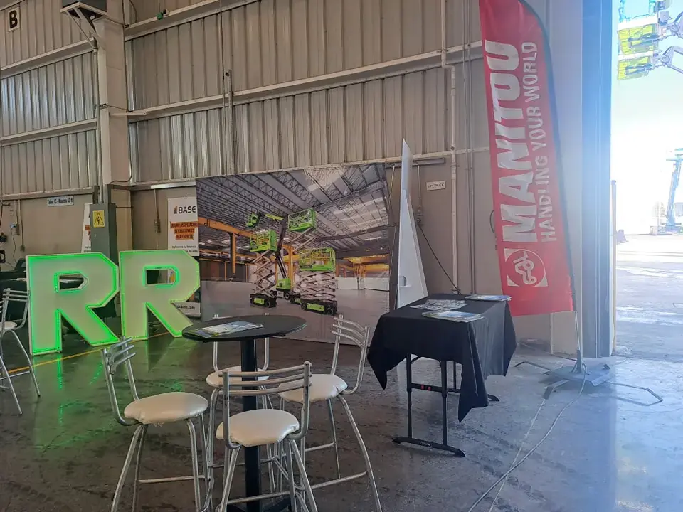 Montaje de activación BTL industrial con letras gigantes iluminadas RR y banderas publicitarias tipo vela Manitou en Monterrey